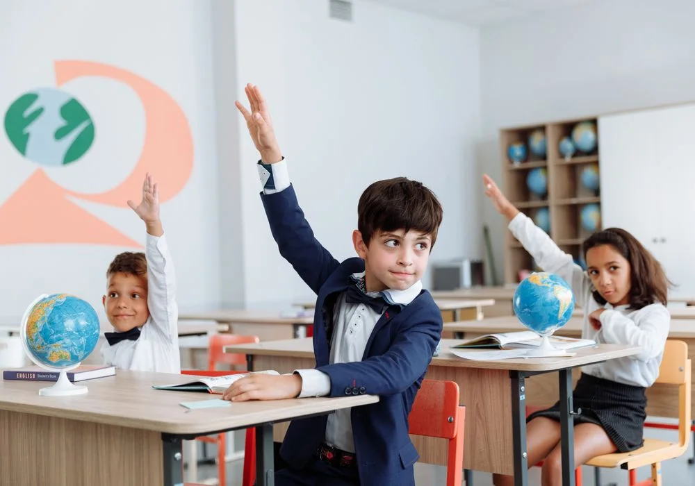 Enfants en classe levant la main