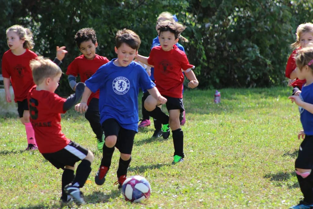 Enfants d'un club de football amateur en plein match sur un terrain herbeux